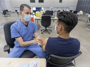 Freddy Calvette vaccinates Daniel Pompa on the last day of the mass vaccination clinic at the Palais des congrès in Montreal on Thursday, Feb. 24, 2022.