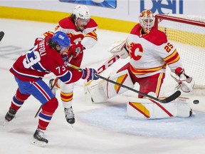 Canadiens winger Tyler Toffoli takes a swing at a loose puck in front of Calgary Flames' Rasmus Andersson and goalie Jacob Markstrom during second period  in Montreal on April 14, 2021.