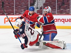 Oliver Bjorkstrand (28) of the Columbus Blue Jackets and Canadiens' Brett Kulak battle for position in front of goaltender Sam Montembeault during the first period at the Bell Centre on Saturday, on Feb. 12, 2022, in Montreal.