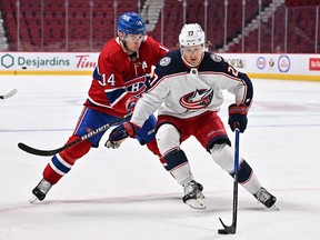 Adam Boqvist (27) of the Columbus Blue Jackets skates the puck against Canadiens' Nick Suzuki (14) during the second period at the Bell Centre on Saturday, Feb. 12, 2022, in Montreal.