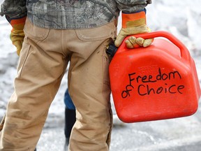 A trucker carries a gas canister as truckers and supporters continue to protest vaccine mandates and other COVID measures in Ottawa on Feb. 9, 2022.