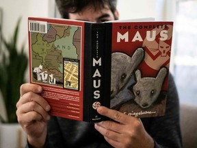This illustration photo taken in Los Angeles, California on January 27, 2022 shows a person holding the graphic novel Maus by Art Spiegelman.