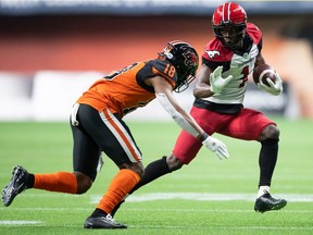 Calgary Stampeders' Hergy Mayala runs with the ball before being tackled by B.C. Lions' Hakeem Johnson in Vancouver, on Oct. 16, 2021.