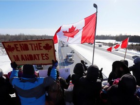 People gather on an overpass to support truckers arriving in a convoy to protest against COVID-19 pandemic health rules for cross-border truck drivers in Ottawa on Jan. 28, 2022.