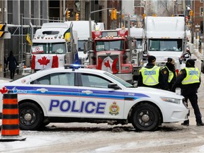 Police patrol a barricade while vehicles block downtown streets as truckers and supporters continue to protest vaccine mandates in Ottawa on February 3, 2022.