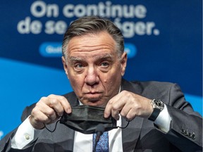 Premier François Legault puts on a mask following a press conference in Montreal on January 13, 2022.