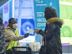 A woman receives a fresh mask at the COVID-19 vaccination centre at the Palais des congrès in Montreal on Jan. 20, 2022.