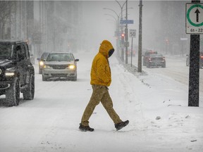 A man crosses René-Lévesque Blvd. on a snowy day in Montreal, Friday February 25, 2022.