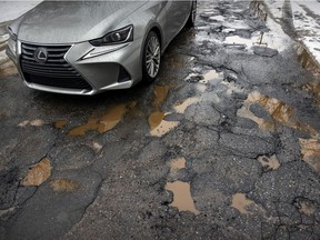 A car passes over a pothole-filled section of asphalt on 44th Ave. in the Lachine borough of Montreal on Monday March 7, 2022.