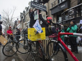 Karim Kammah attaches a sign at the corner of St-Denis and Roy Sts. in Montreal on Saturday, March 12, 2022, in a ceremony to honour Robert "Bicycle Bob" Silverman. Silverman was one of the co-founders of the activist group Le Monde à bicyclette (MAB). Silverman died last Feb. 20 at the age of 88.