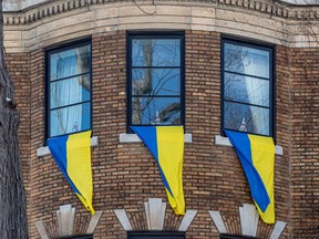Ukrainian flags hang from the windows of Serge Sasseville's home directly across from the middle building of the three building Russian consulate complex in Montreal.