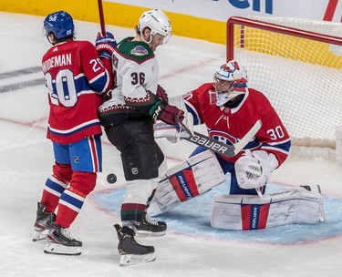 A puck sails through the crease of Montreal Canadiens goaltender Cayden Primeau (30) with teammate defenseman Chris Wideman (20) and Arizona Coyotes right wing Christian Fischer (36) at the doorstep during 3rd period NHL action at the Bell Centre in Montreal on Tuesday, March 15, 2022.