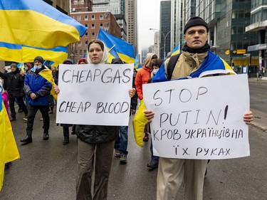 A couple carry signs during a march through downtown Montreal on Saturday, March 19, 2022, in support of Ukraine and to denounce Russia and Vladimir Putin.