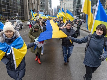 Participants carry a long banner with the colours of the Ukrainian flag during a march through downtown Montreal on Saturday, March 19, 2022, in support of Ukraine and to denounce Russia and Vladimir Putin.