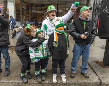 Rocky Roberts, rear left, waves to friends with his children Madison, left, Kinny and Kelton, attend Montreal's St. Patrick's parade with friend Ross Osborne on March 20, 2022