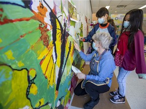 Artist Madeleine Turgeon works with Grade 2 students Miya Alyanne Rimbao and Peter Lagogiannis as they help paint a school-wide mural project at Forest Hill Elementary School Junior Campus in St-Lazare, on Monday.