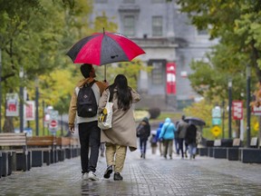 A couple share an umbrella while walking on the McGill University campus.