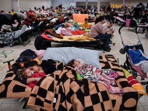 A mother sleeps with her children among many others in a temporary shelter hosting the Ukrainian refugees located in a former shopping centre near the city of Przemysl, on March 8, 2022.