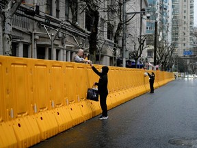 People pass food to residents over the barriers of an area under lockdown, amid the COVID-19 pandemic, in Shanghai, China.