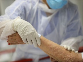 A health-care worker treats an elderly patient in hospital.