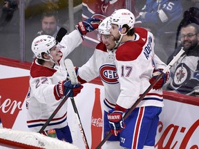 Montreal Canadiens' Nick Suzuki, centre, celebrates his goal against the Winnipeg Jets with Cole Caufield  and Josh Anderson during first period in Winnipeg on March 1, 2022.