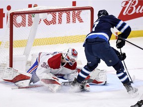 Jets' Adam Lowry scores on Canadiens goaltender Sam Montembeault Tuesday night in Winnipeg. It was a rough night for Montembeault, who was pulled in the third period after giving up seven goals on 23 shots.