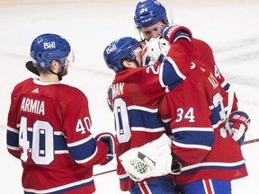 Canadiens goaltender Jake Allen (34) is hugged by teammates after defeating the Toronto Maple Leafs in Montreal on Saturday, March 26, 2022.