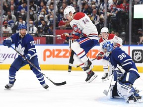 Canadiens' Suzuki (14) jumps as he attempts to screen a shot on Maple Leafs goalie Jack Campbell at Scotiabank Arena on Oct. 13, 2021, in Toronto.