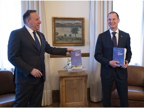 Quebec Premier François Legault receives a copy of the provincial budget speech from Quebec Finance Minister Eric Girard Tuesday, March 22, 2022 at the premier's office in Quebec City.