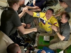 Russian cosmonauts arrive wearing yellow and blue flight suits at the International Space Station after docking their Soyuz capsule March 18, 2022 in a still image from video.