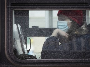 A woman waits on a bus outside the Parc métro station on Monday March 28, 2022.