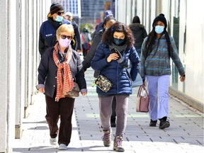 Masked pedestrians walk through the Quartier des spectacles on April 11, 2022.