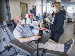 A man in a chair speaks to a nurse while donating blood.