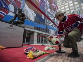 Patrick-Joseph Dufour lays flowers at the statue of Guy Lafleur outside the Bell Centre in Montreal on Friday, April 22, 2022.