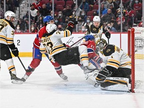 Mathieu Perreault #85 of the Montreal Canadiens takes down Charlie McAvoy #73 of the Boston Bruins near goaltender Jeremy Swayman #1 during the second period at Centre Bell on April 24, 2022 in Montreal.
