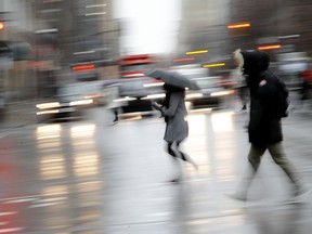 Pedestrians dash across Sherbrooke St. as a cold rain falls on Montreal April 8, 2019.