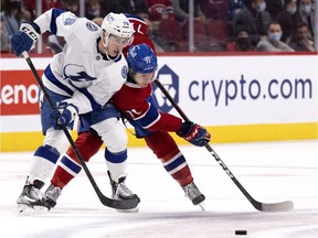 Canadiens' Jake Evans (71) and Tampa Bay Lightning's Ross Colton (79) struggle to recover the puck in Montreal on Dec. 7, 2021.