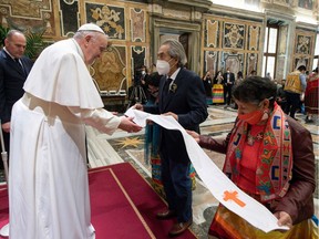 This photo taken on Friday, April 1, 2022, shows Pope Francis receiving a stole from former national chief of Canada's Assembly of First Nations (AFN), Phil Fontaine, centre, during an audience to Canada's Indigenous delegations at the Vatican. The pope Friday apologized for the decades of abuse at church-run residential schools in Canada and said he would visit the country in late July.