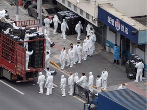 This photo, taken on April 5, 2022, shows people wearing personal protective equipment as they transfer daily food supplies and necessities for local residents during the COVID-19 lockdown in Shanghai.