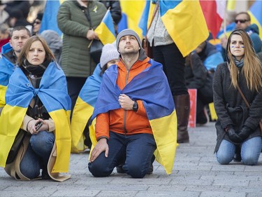 People take a knee during a rally in support of Ukraine outside the Notre-Dame Basilica in Montreal on Saturday, April 2, 2022.