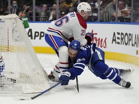 Maple Leafs' Auston Matthews (34) gets his stick on the puck as he battles Canadiens' Jeff Petry behind the net in Toronto on Saturday, April 9, 2022.