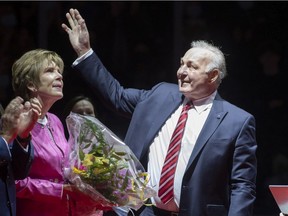 NHL hockey legend Guy Lafleur waves to Quebec Remparts fans as his wife Lise looks on during a ceremony to retire his No. 4 from the QMJHL on Oct. 28, 2021, at the Videotron Centre in Quebec City.