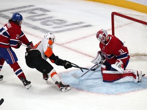 Flyers' Morgan Frost beats Canadiens goalie Carey Price as defenceman Alexander Romanov defends during the third period at the Bell Centre Thursday night.