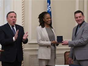 National Secretary General Siegfried Peters, right, and Quebec Premier François Legault pose with MNA Shirley Dorismond as she receives her National Assembly medal after being sworn in, following a byelection, Tuesday, April 26, 2022 at the legislature in Quebec City.