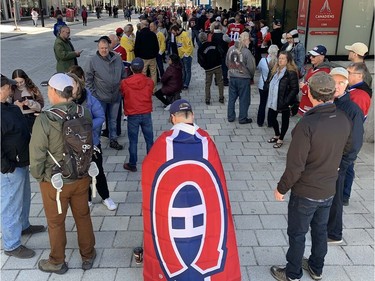 Robert Belanger waits patiently with a Habs flag as a cape along Av. des Canadiens-de-Montreal on Sunday May 1, 2022, prior to the opening of the Bell Centre, where Lafleur's body will lie in state for the next two days.