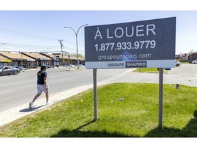 A man walks past a real estate sign offering commercial space for rent on St-Charles Blvd. in Pierrefonds.