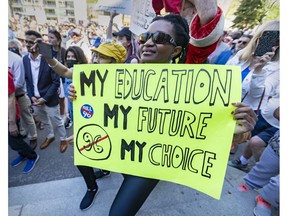 Eine Frau hält am Samstag, den 14. Mai 2022, während einer Kundgebung in Montreal ein Schild, um sich gegen Bill 96 zu stellen.