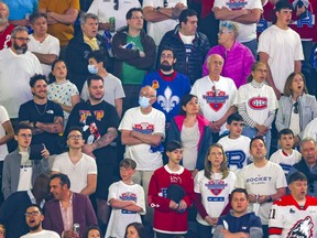 A couple of mask-wearing Laval Rocket fans are surrounded by maskless fans — on the first day after mask wearing restrictions in Quebec were lifted — in a playoff game against the Syracuse Crunch at the Place Bell Sports Complex in Laval on Saturday, May 14, 2022.