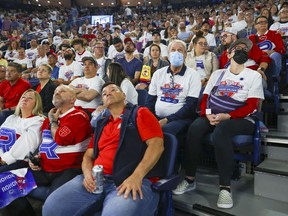 A couple of mask-wearing Laval Rocket fans are surrounded by maskless fans during  a playoff game against the Syracuse Crunch at the Place Bell Sports Complex in Laval on Saturday May 14, 2022, the first day mask restrictions were lifted in Quebec.