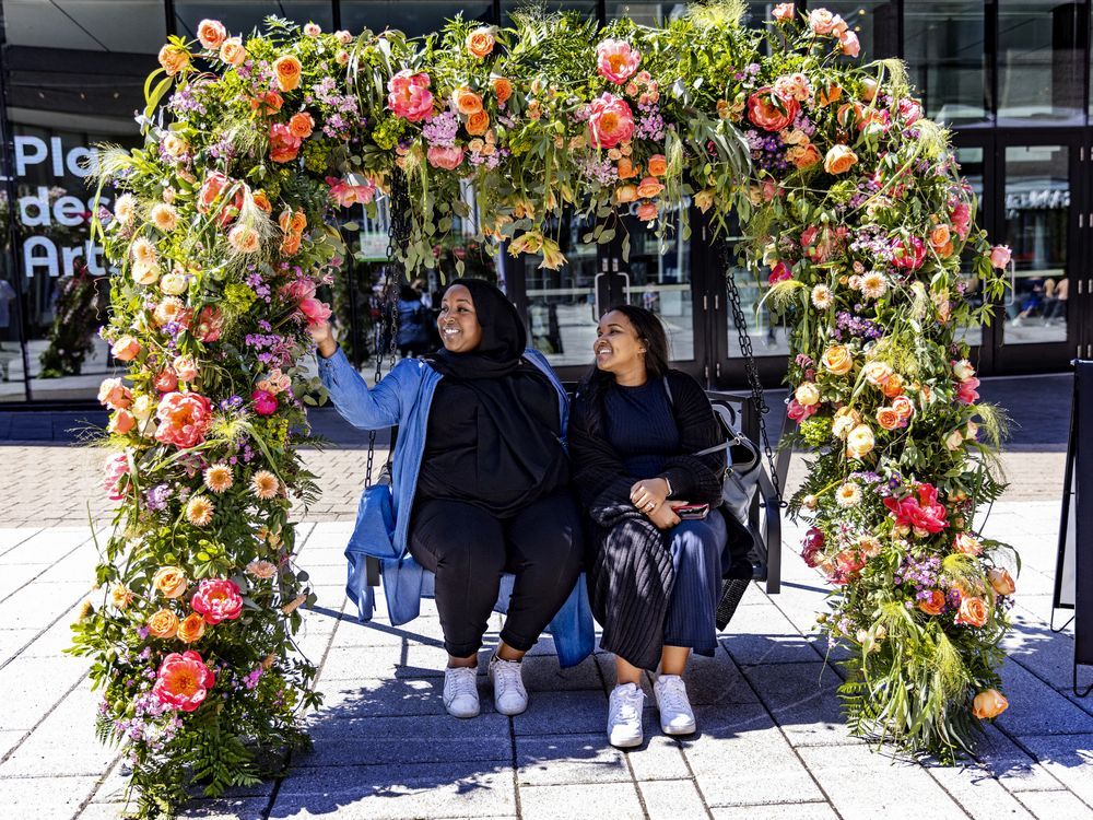 Moudane Daahir, left, and Kadidja Hadji-Farah try out the flower-covered swing at the Fleurs de Ville exhibit in Montreal's Quartier des Spectacles on May 20, 2022.